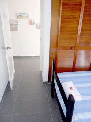 Ein Zimmer mit einem Bett, einer Holztür und einem Fliesenboden.