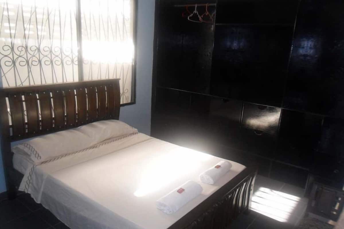 A bedroom with a bed, a radiator, and a TV mounted on the wall.