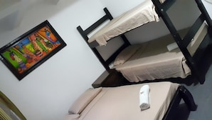 Une chambre avec des lits superposés, un tableau accroché au mur et une serviette roulée sur le lit du bas.