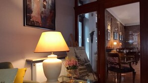 Een gezellige zithoek met een lamp, een tafel met een bloemenvaas, en een ingelijst beeld op de muur.