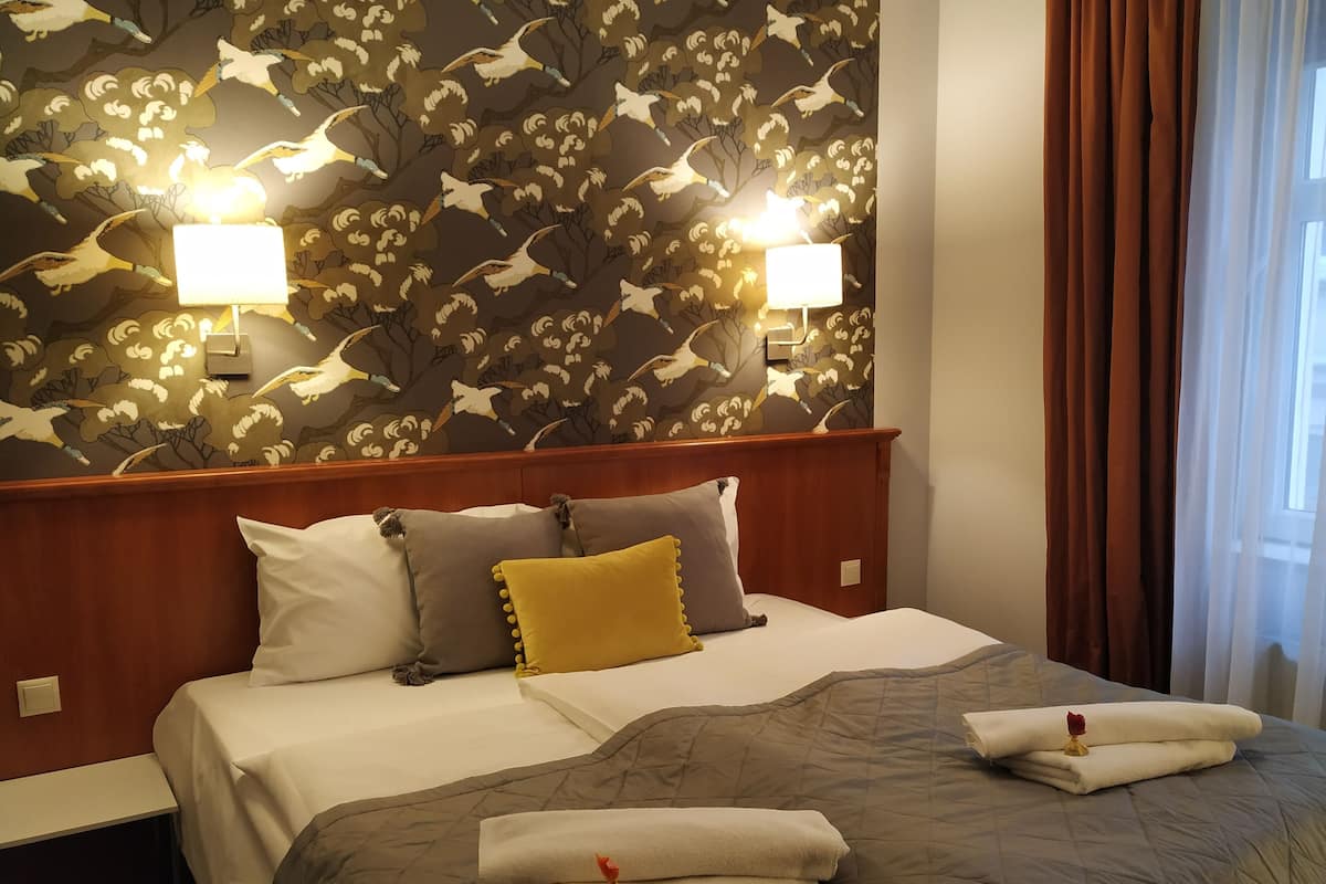 Een hotelkamer met een bed, twee wandlampen en bloemenbehang.
