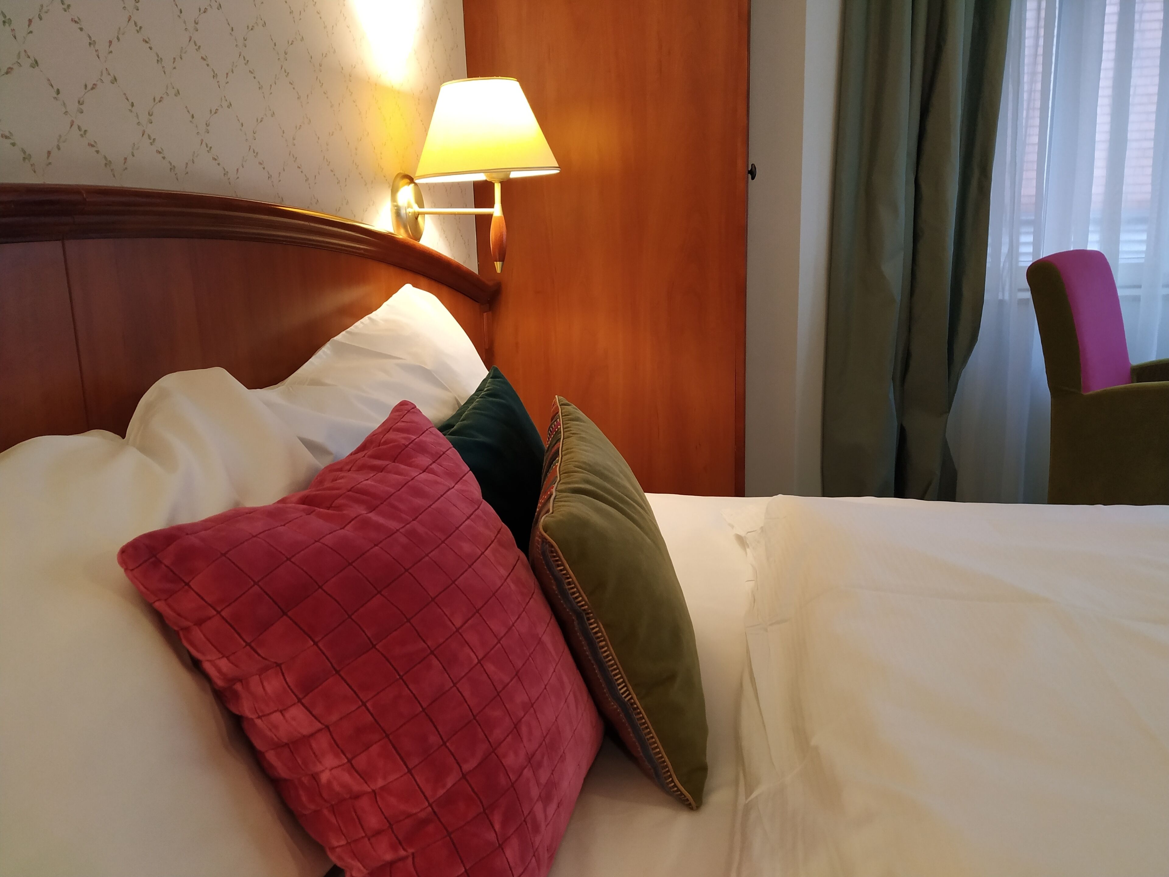 Una cama bien hecha con varias almohadas en una habitación de hotel.