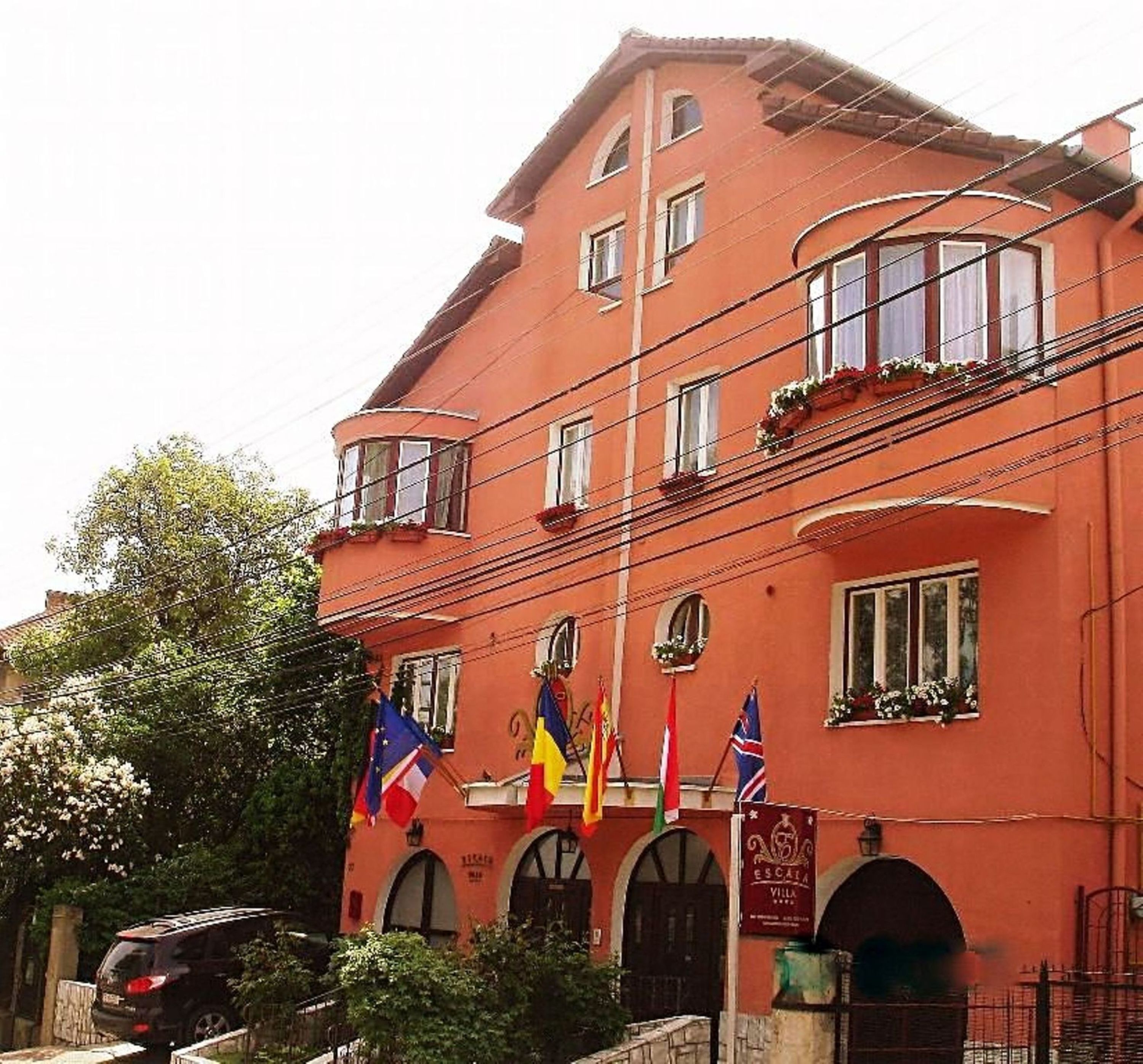 Un bâtiment rouge doté de nombreuses fenêtres et de balcons, ainsi que de drapeaux et d’une enseigne indiquant qu’il s’agit d’un hôtel.