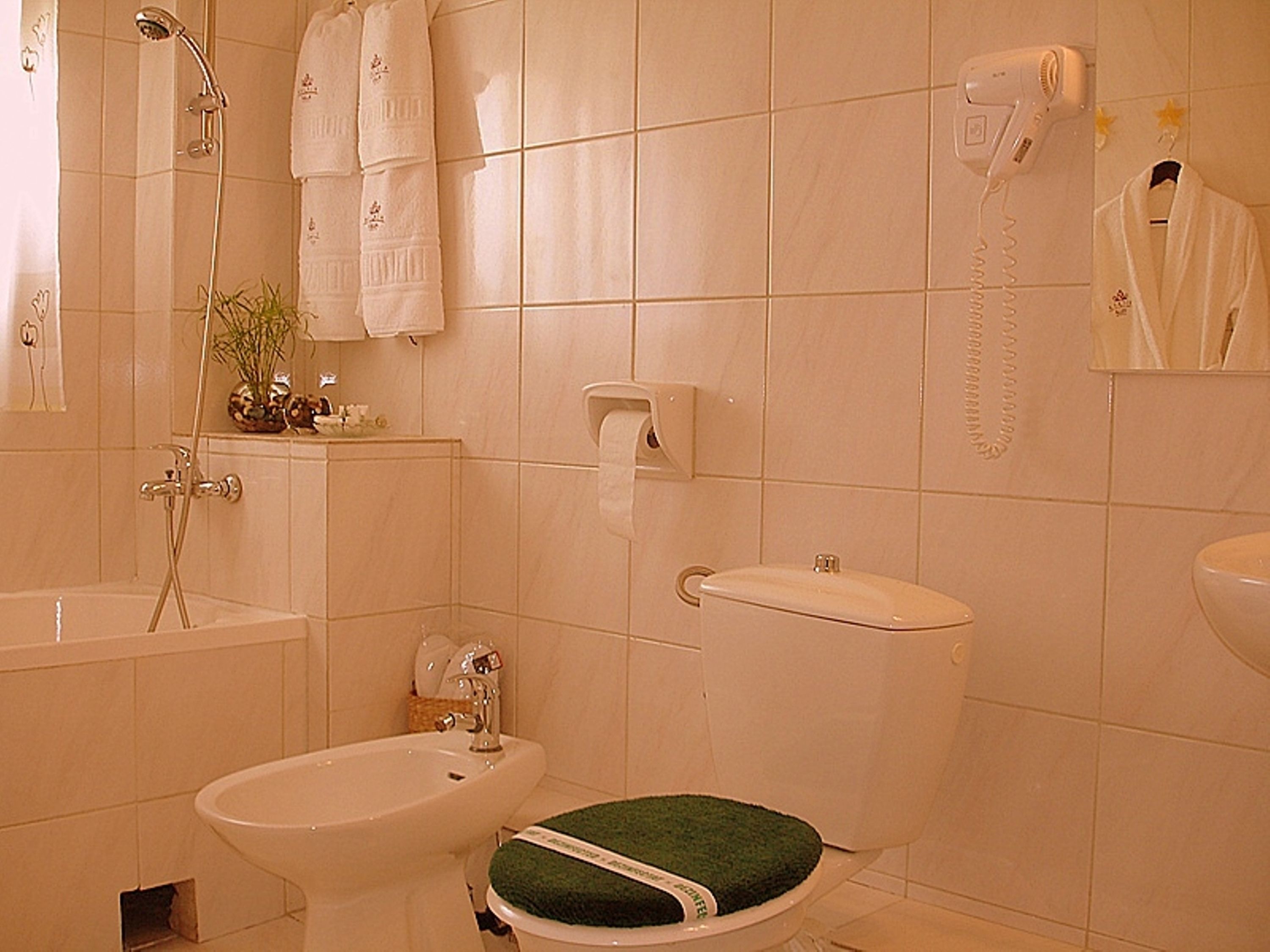 Une salle de bain équipée d’une baignoire, d’un lavabo, de toilettes et d’un sèche-cheveux fixé au mur.
