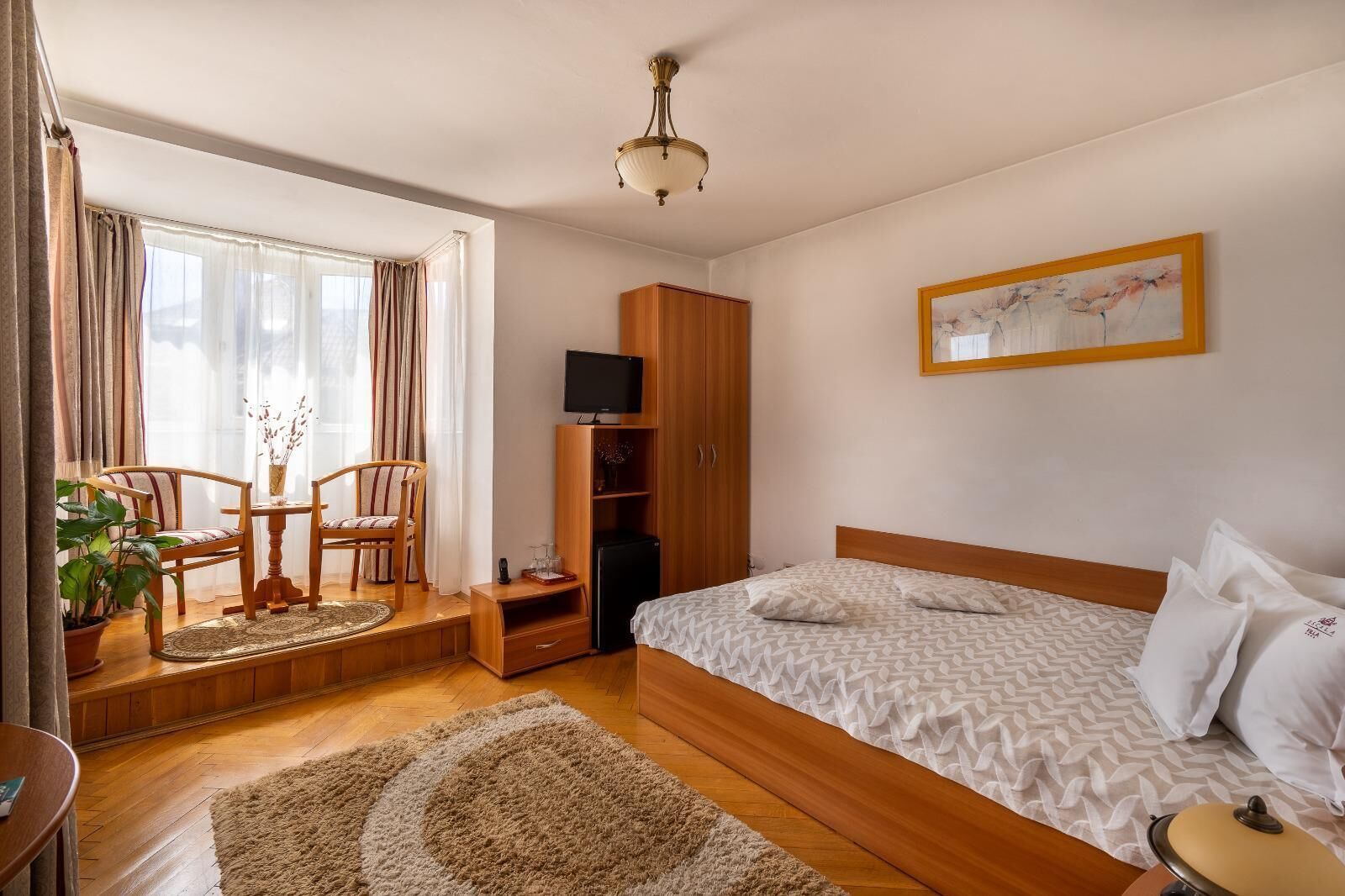 A hotel room with a bed, a desk, a chair, a television, and a wardrobe.