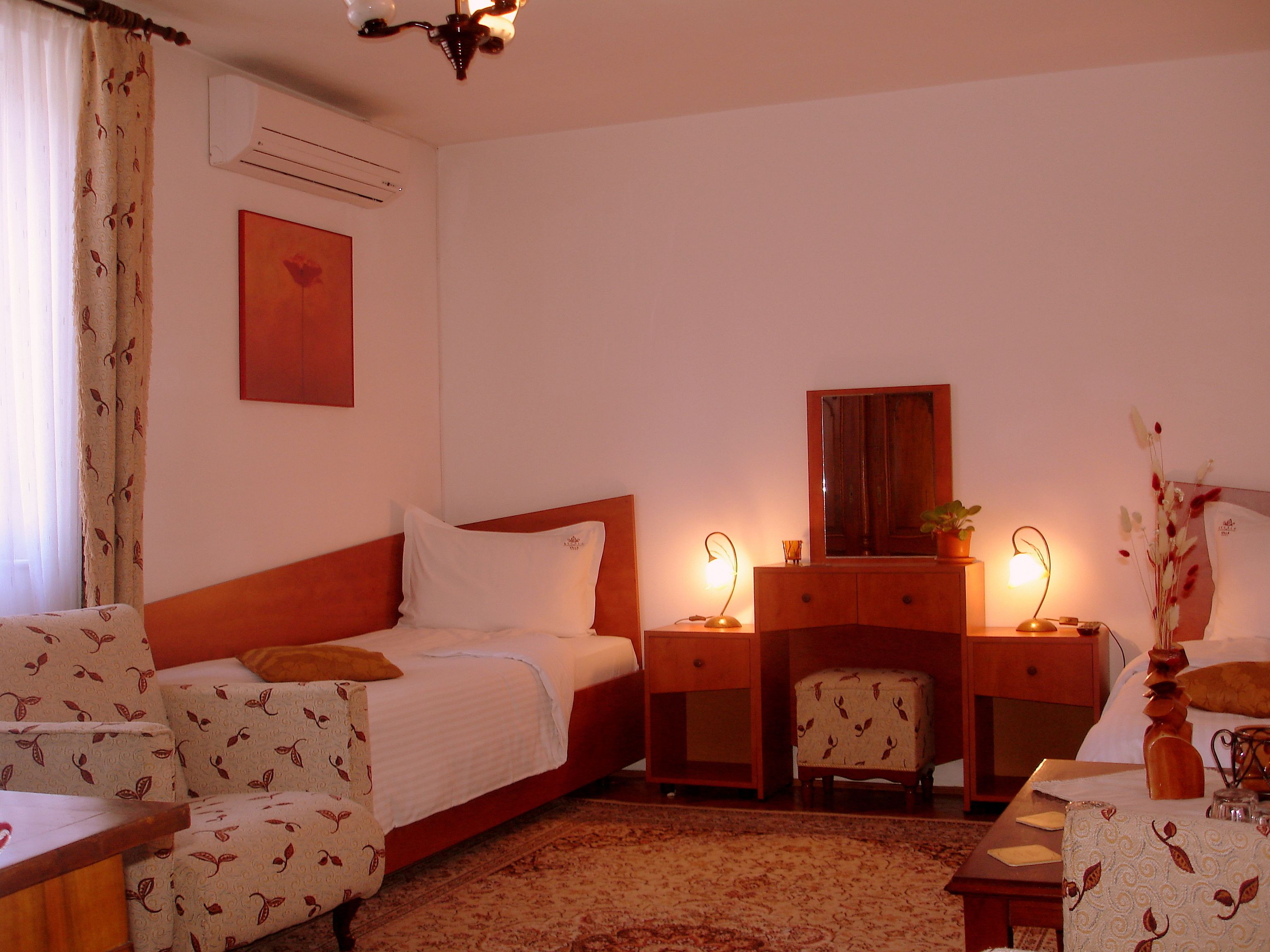 A hotel room with a bed, a desk, a chair, a dresser, and a mirror.
