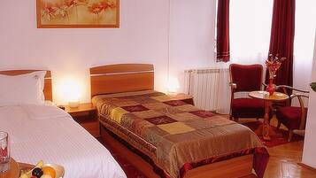 Ein Hotelzimmer mit einem Bett, Nachttischen, einem Sessel, einem kleinen Tisch mit einer Vase und einem Bild an der Wand.