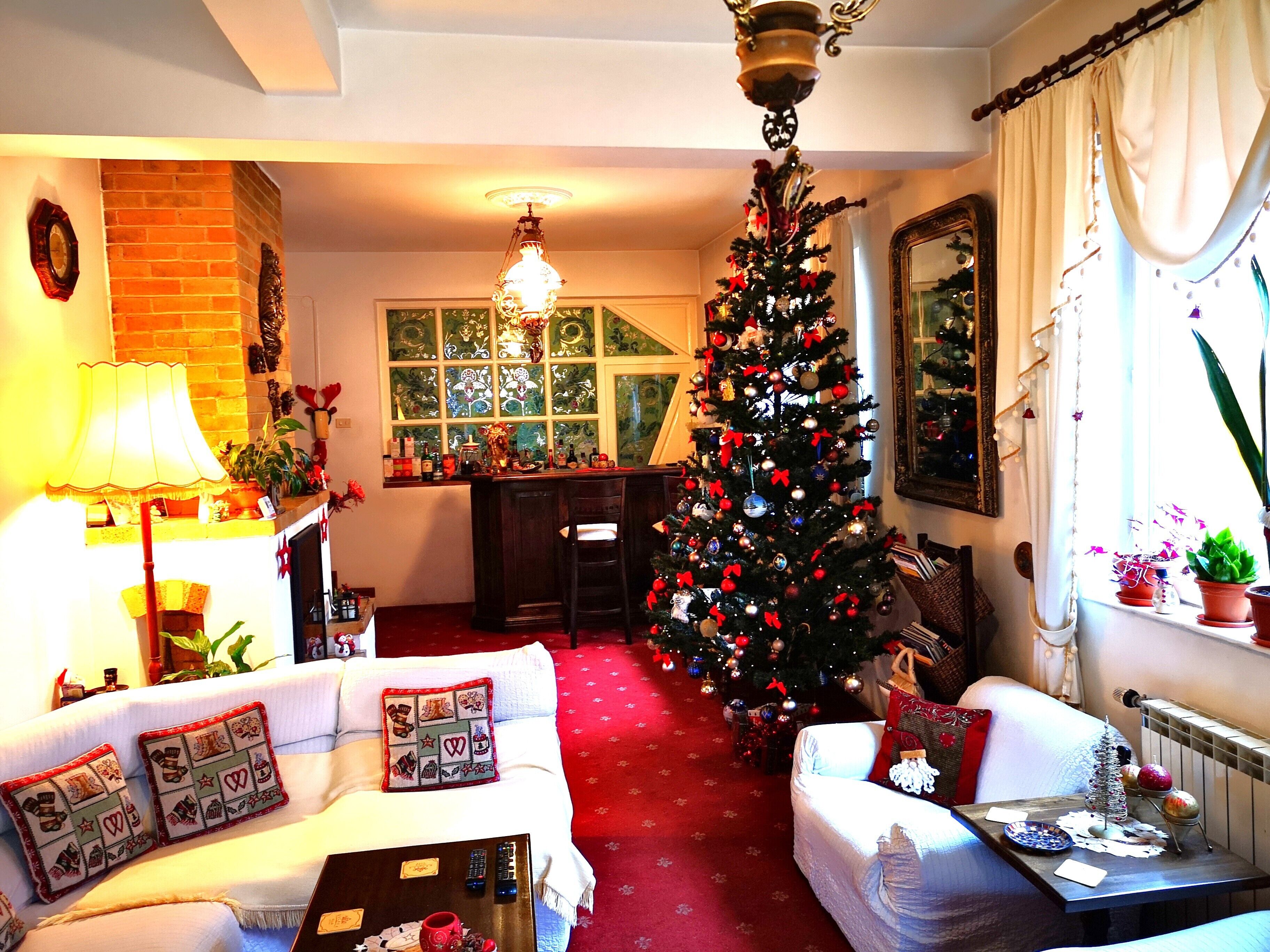 Una sala acogedora con chimenea, un árbol de Navidad y un comedor con candelabro.
