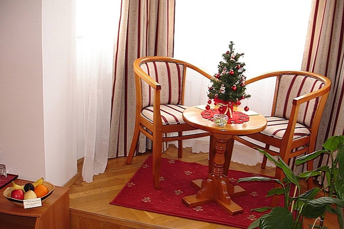 Un comedor con una mesa de madera y dos sillas, un pequeño árbol de Navidad y un frutero sobre un mueble de madera.