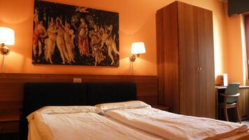 A hotel room with a large bed, two bedside lamps, a wooden wardrobe, and a painting on the wall.