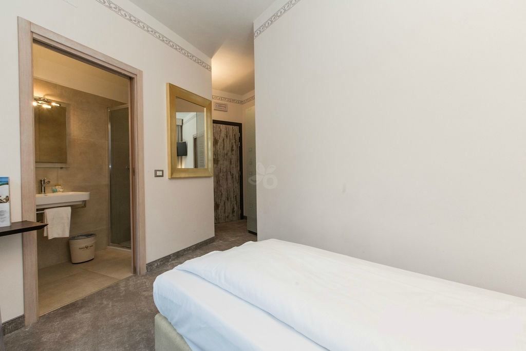A hotel room with a bed, a bathroom with a sink, and a mirror.