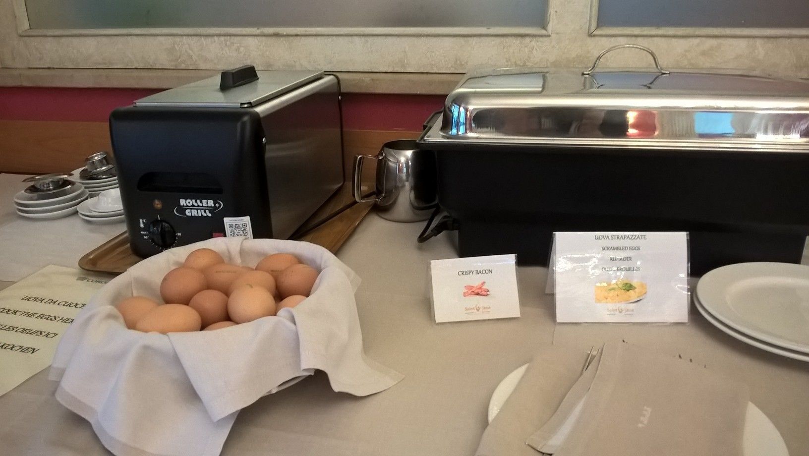 A breakfast buffet setup with a toaster, a coffee maker, and a bowl of eggs.