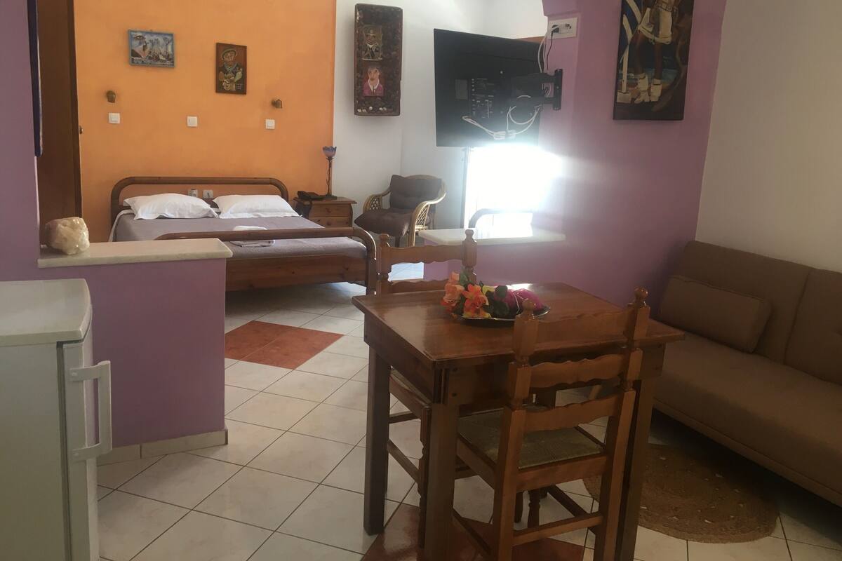 Une pièce comprenant un lit, une table à manger avec des chaises, un canapé et un téléviseur fixé au mur.