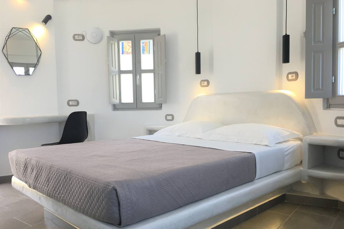 Une chambre moderne avec un grand lit, des tables de chevet, un bureau et un miroir.