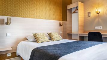 A hotel room with a bed, a desk, and a wardrobe.