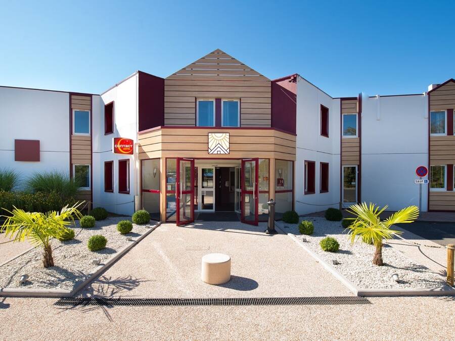 Un hotel moderno con entrada central, varias ventanas y un letrero que indica que es un hotel de contacto.