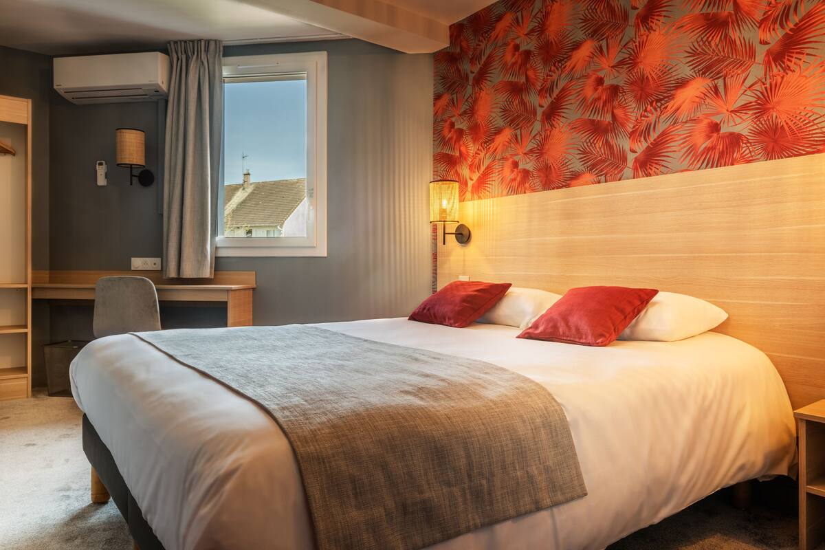 Una habitación de hotel con una cama grande, un escritorio y una ventana.