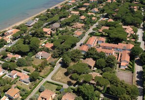 An aerial view of a residential area with houses, trees, and a beach.