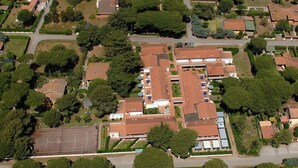 Vue aérienne d’un quartier résidentiel avec de nombreuses maisons, un court de tennis et de la végétation environnante.