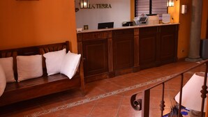 Un vestíbulo con un banco de madera, una recepción y un suelo de baldosas.