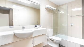 A modern bathroom with a white sink, toilet, and glass-enclosed shower.