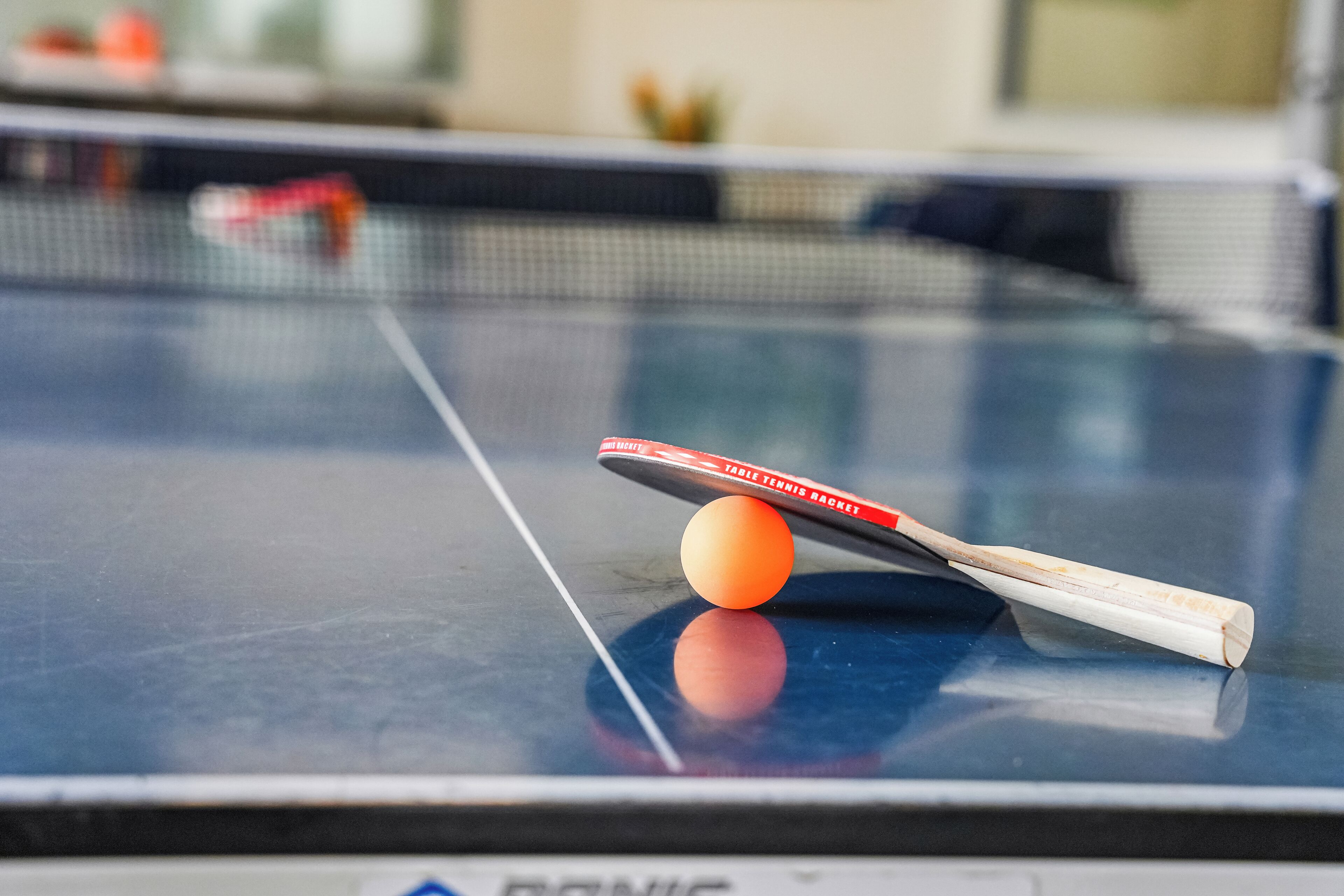 A table tennis table with a ball and paddle.