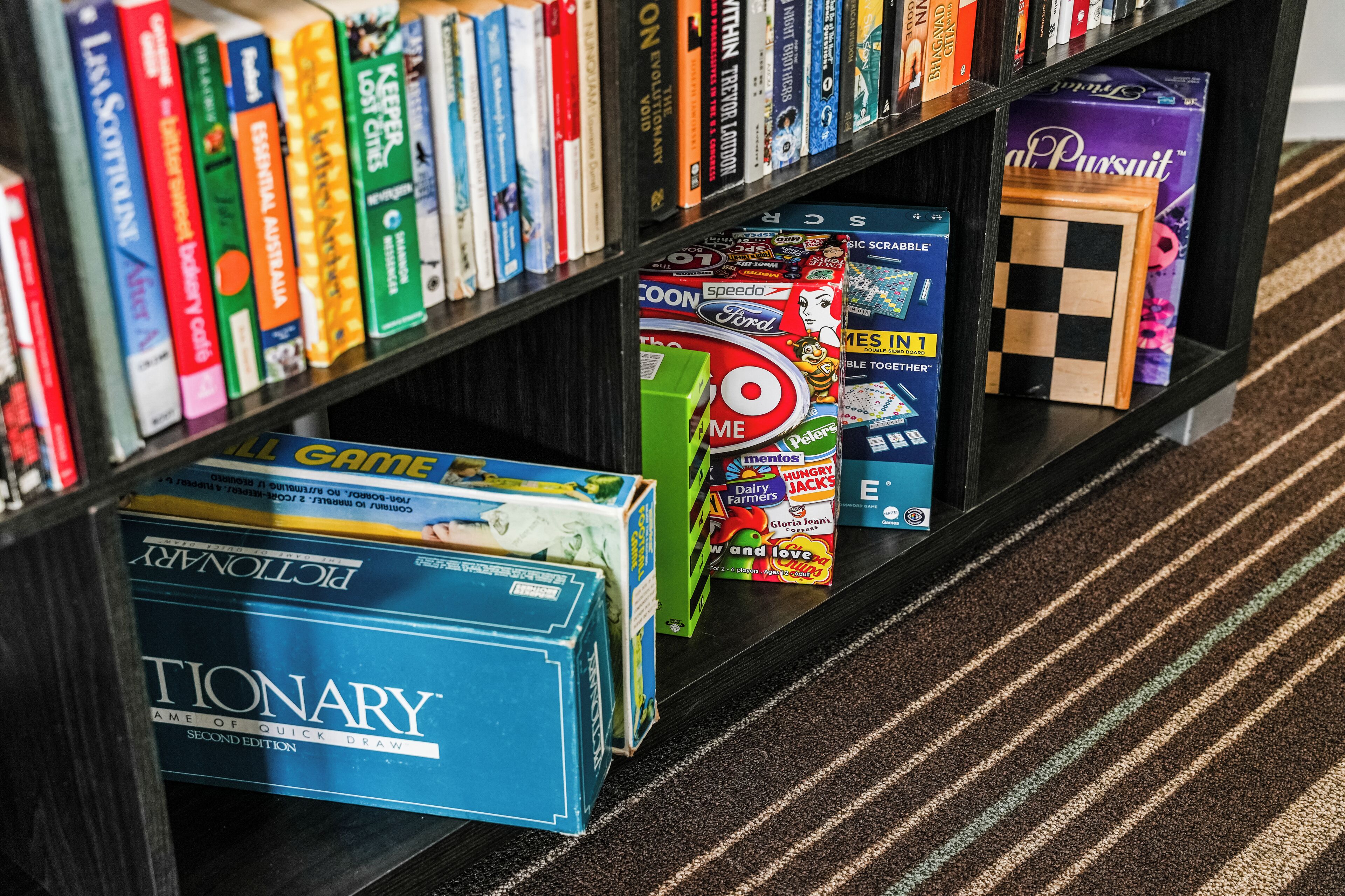 A bookshelf with various board games and books.