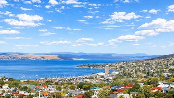A coastal town with a marina, residential buildings, and a clear view of the sea and distant hills.
