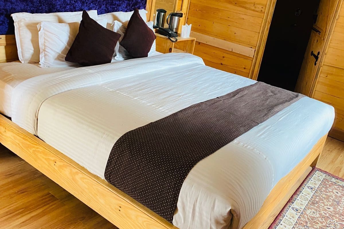 A wooden room with a large bed, a blue headboard, and a framed picture of a giraffe.