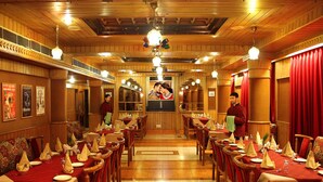 Un restaurant amb panells de fusta, tovallons vermells i diverses taules de dinar.