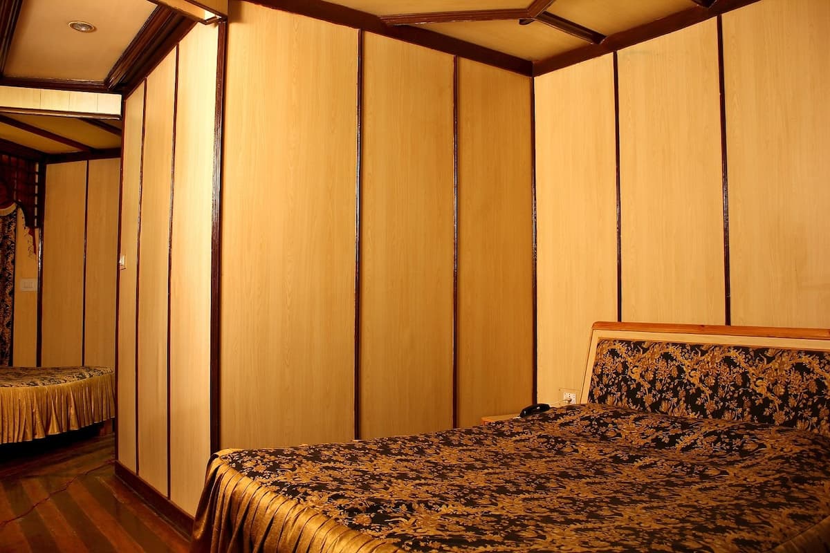 A room with a bed, wooden panel walls, and a patterned bedspread.
