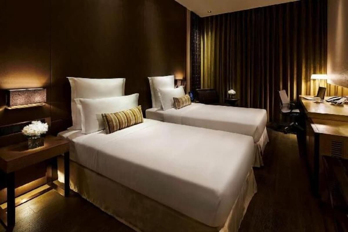 A hotel room with two beds, a desk, and a chair.