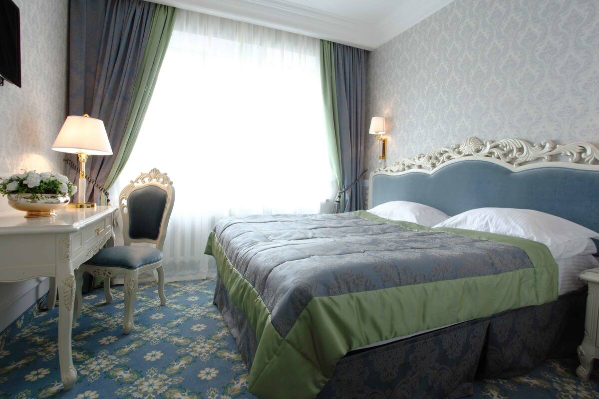 Een hotelkamer met een bed, bureau, stoel en lamp.