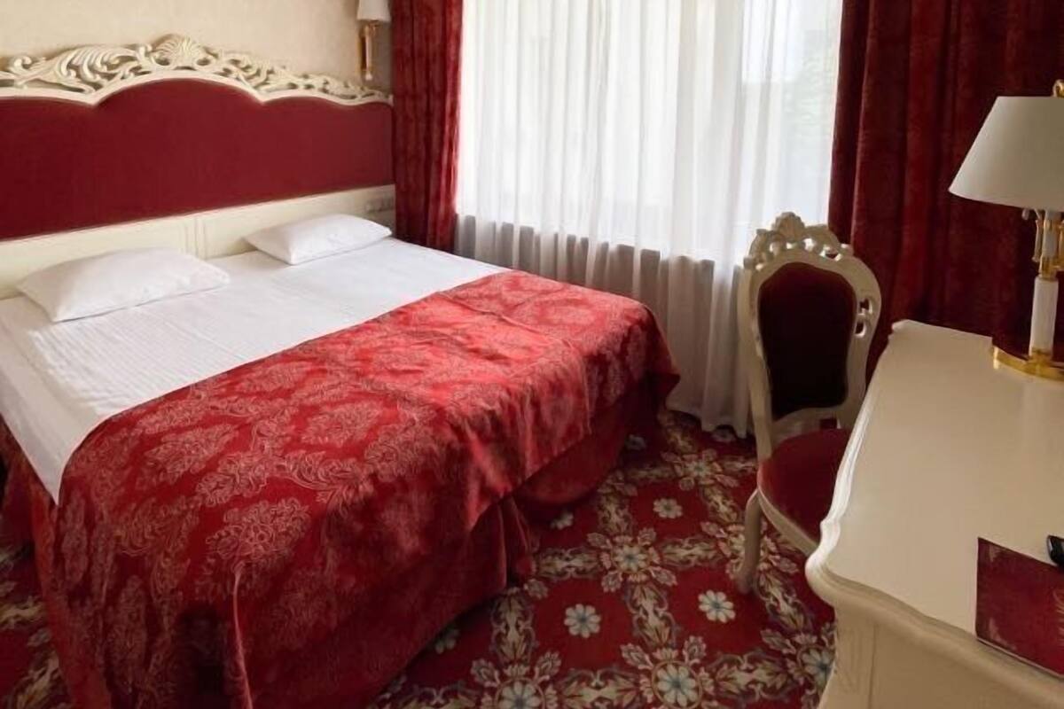 Een hotelkamer met een groot bed, een bureau met lamp, een stoel en een kroonluchter.