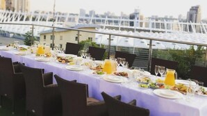 Una larga mesa dispuesta para una comida con vista a la ciudad al fondo.
