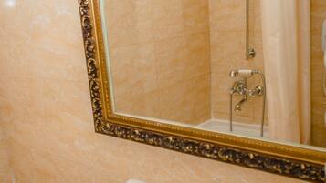 Un baño con un espejo grande, un lavamanos y una ducha.