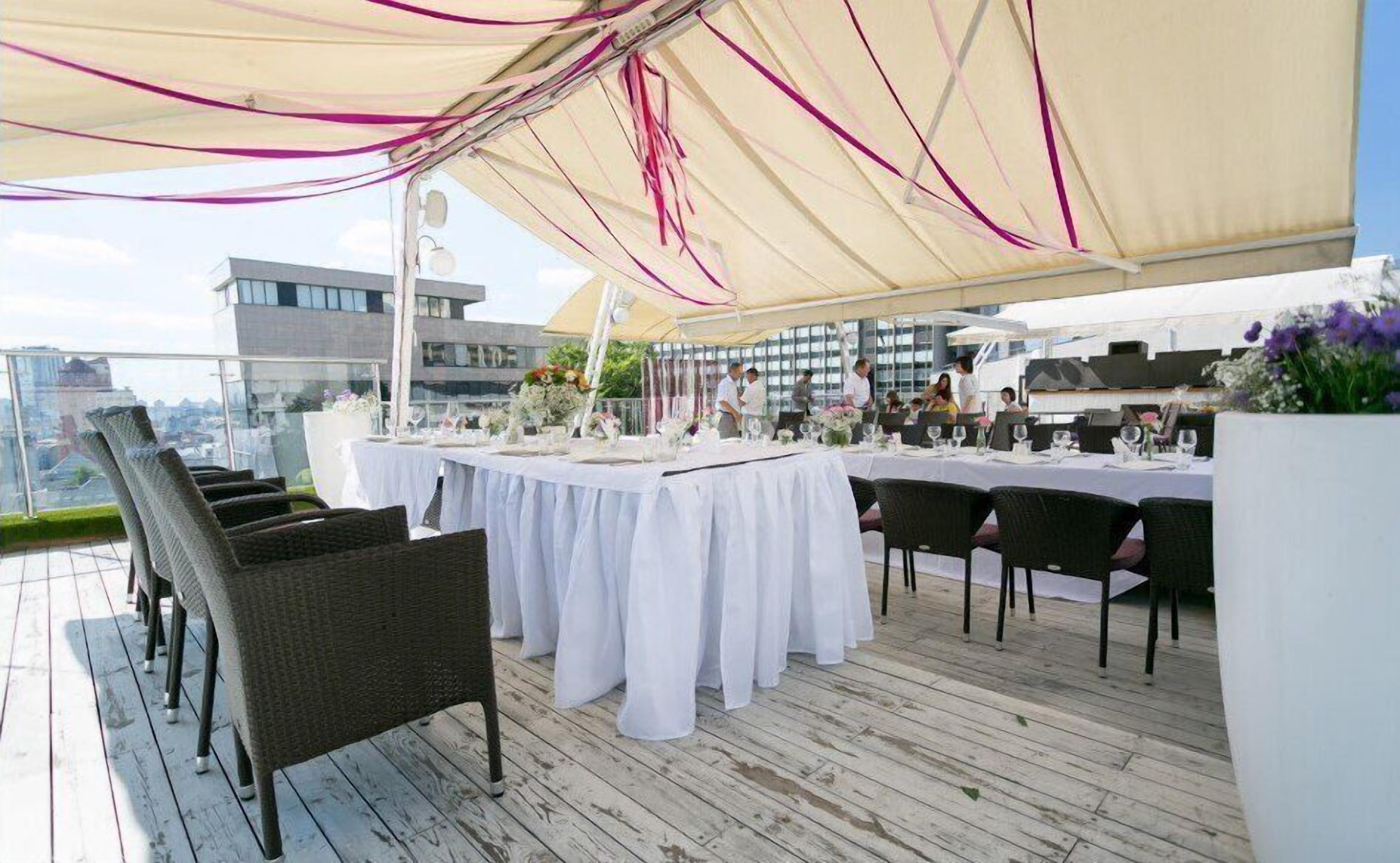Un área de comedor al aire libre con manteles blancos, sillas de mimbre y un dosel.