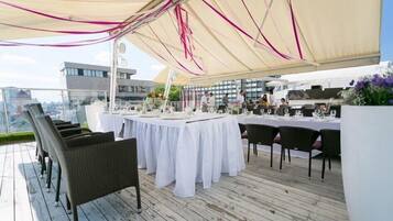 Un área de comedor al aire libre con manteles blancos, sillas de mimbre y un dosel.