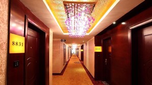 A hotel hallway with a carpeted floor, wooden doors, and a chandelier. - Guangdong Jin Bao Lai Hotel (Guangzhou)