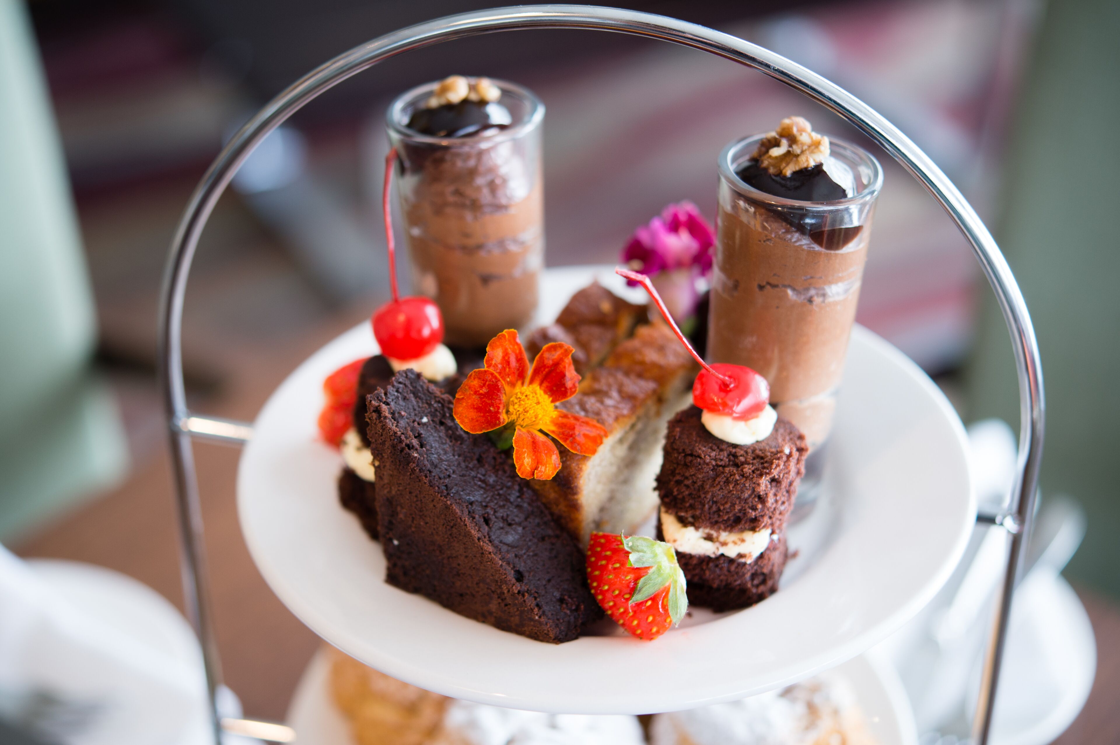 A dessert tray with various sweets and a flower decoration.