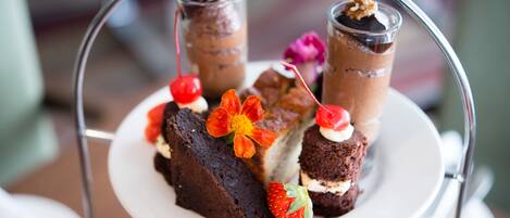 A dessert tray with various sweets and a flower decoration.