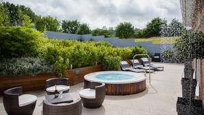A rooftop patio with a hot tub, wicker furniture, and a view of the surrounding greenery. - Lakeside Park Hotel & Spa (Ryde)