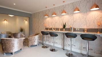 A modern bar area with bar stools, a countertop, and pendant lighting.