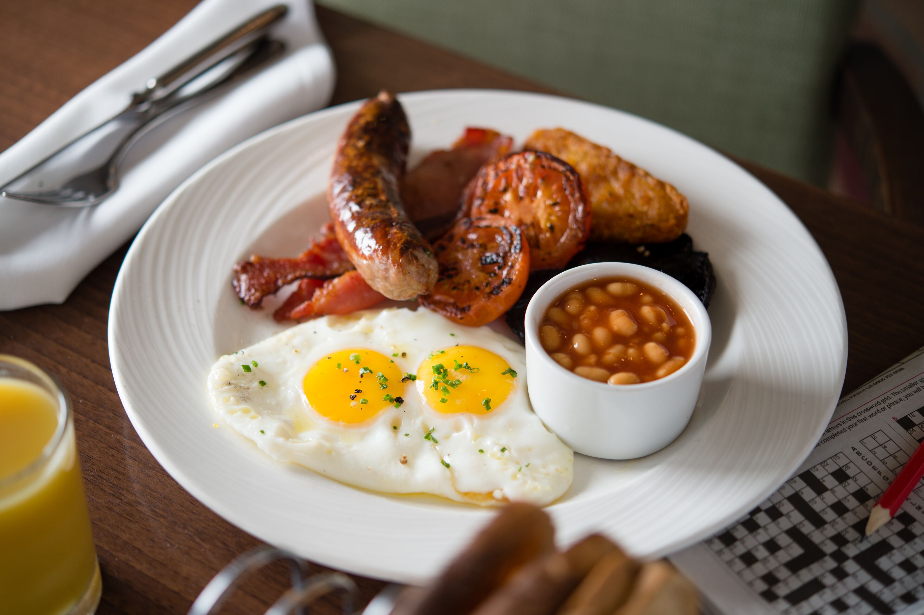 A plate of breakfast food including sausages, bacon, eggs, and baked beans.