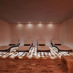 Relax in a serene spa room with lounge chairs and a unique textured wall design.