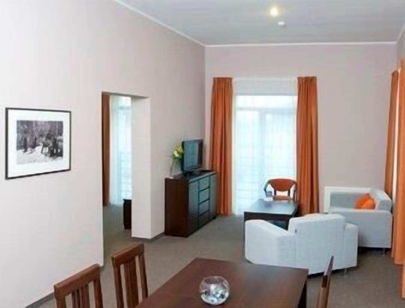 A modern living room with a dining area, a television on a cabinet, and a framed picture on the wall.