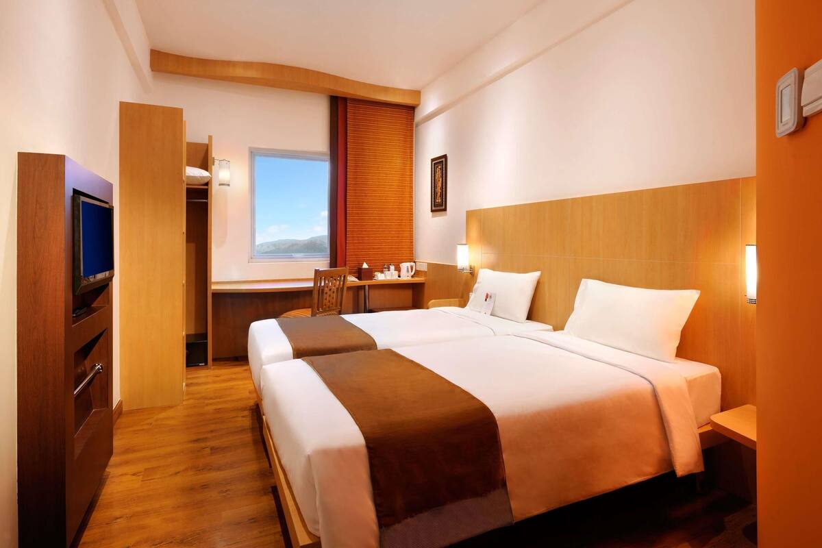 A hotel room with a bed, a desk, a TV, and a window with a view.