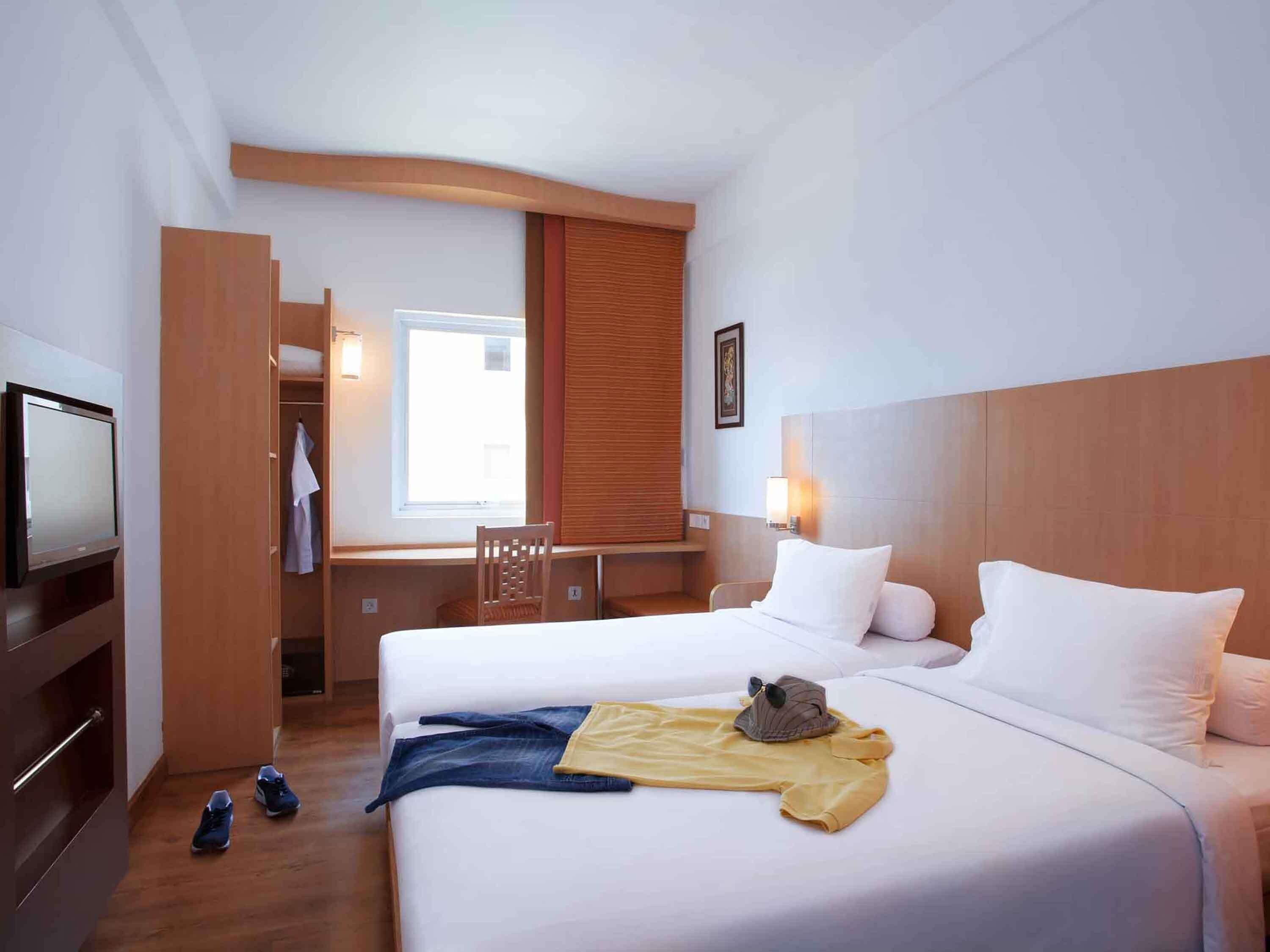 A hotel room with a bed, a desk, a television, and a window.