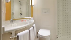 Une salle de bain moderne avec un lavabo blanc, un miroir et des toilettes.