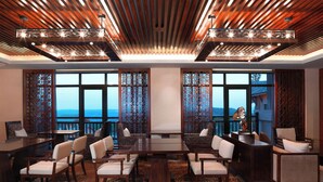 Un salón de conferencias con techo de madera, ventanas amplias y vista al océano.
